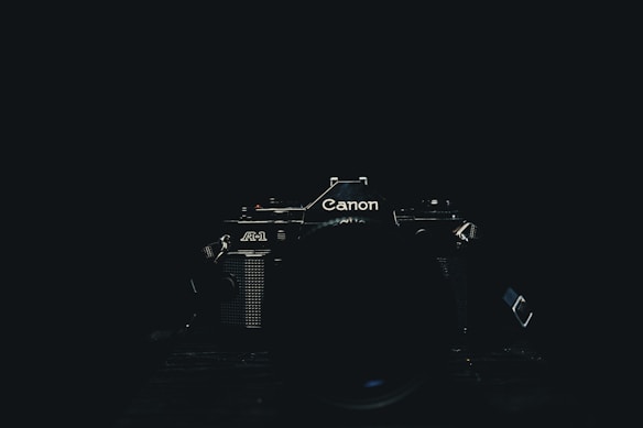 A classic Canon camera is centered in low light, emphasizing its logo and design details on the dark background.