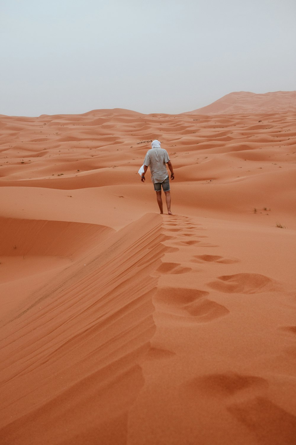 man wearing gray shirt walking on desert
