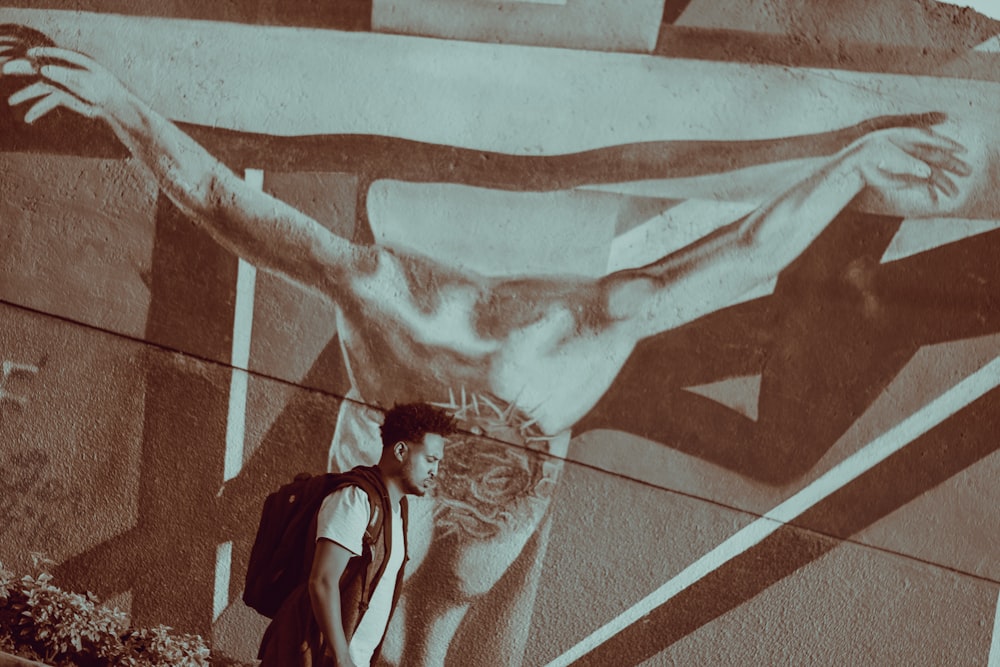 a man standing in front of a painting of jesus on a wall