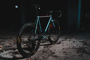A sleek, dark-toned e-bike leaning against a minimalist workshop wall with subtle lighting.