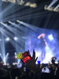 A vibrant neon-lit concert stage with fans holding light sticks, capturing the energy of K-pop.