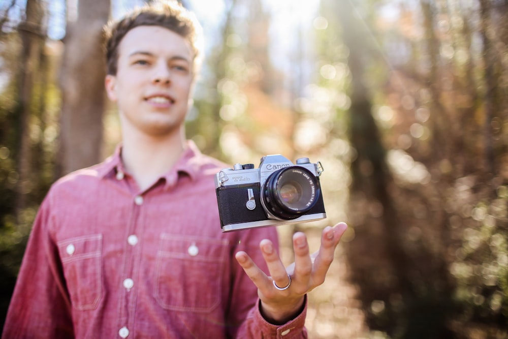 man holding black and gray camera at daytime