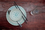 A rustic wooden table set with elegant ceramic plates and stainless steel cutlery.