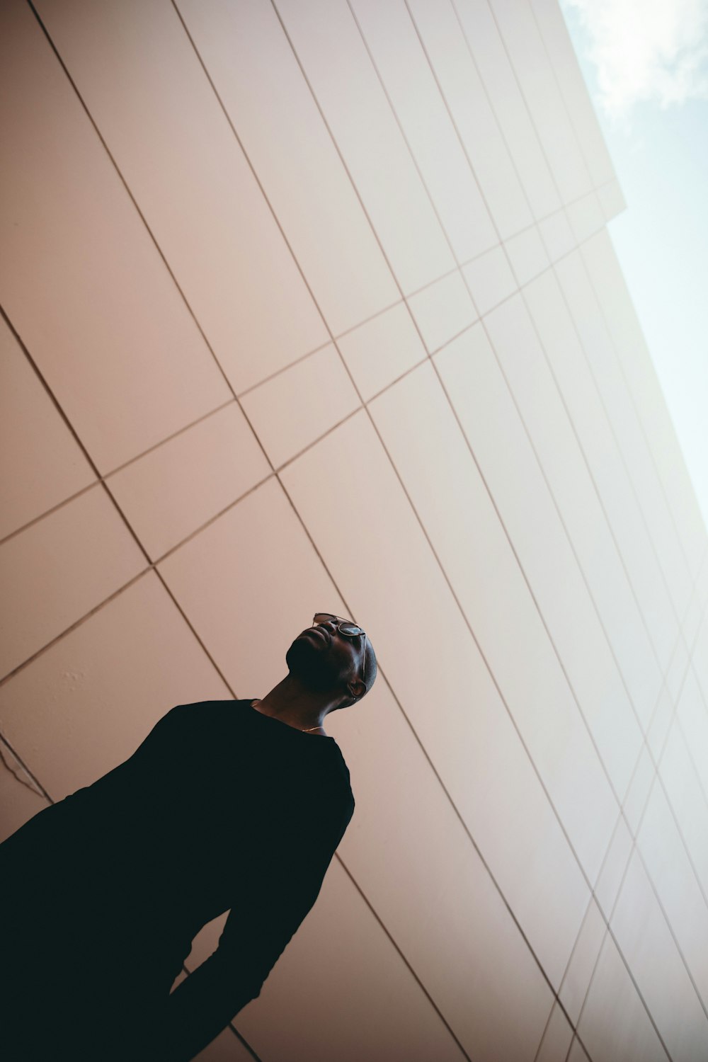 worm's-eye view photography of man standing near beige building