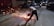 A person is using a power tool to cut through metal rods at night on the side of a road. Sparks are flying from the tool as it makes contact with the metal. There are other vehicles and people visible in the background, suggesting an urban environment.