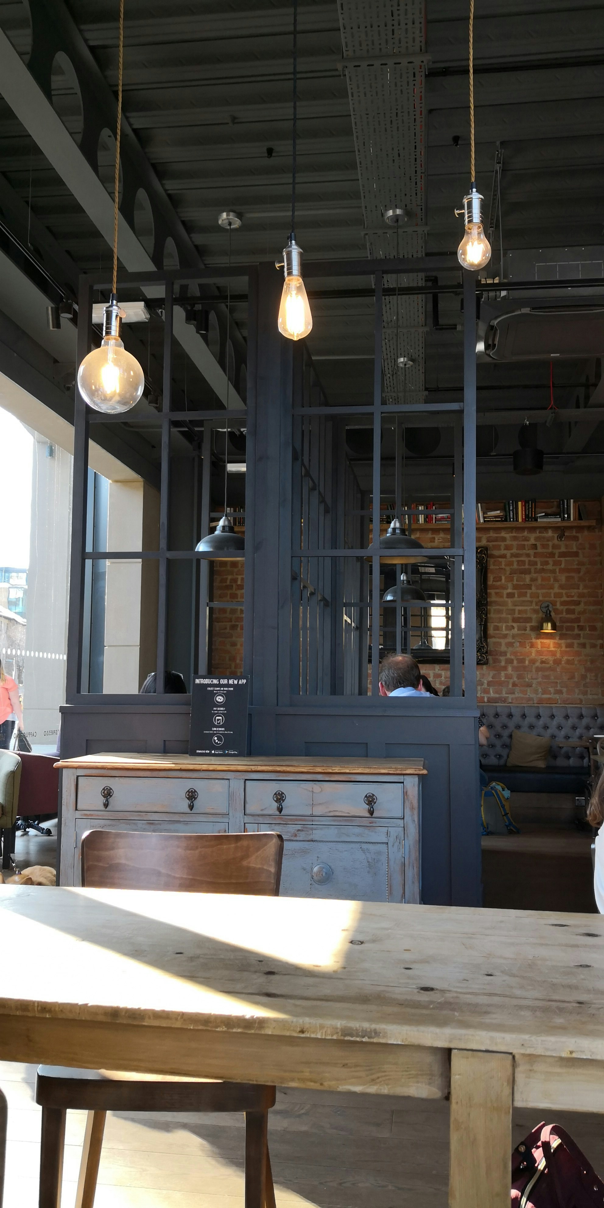 Rustic wooden café interior with coffee estate view and hanging Edison bulbs