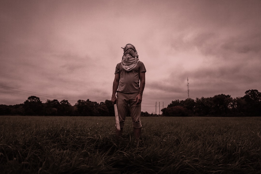 person holding gray machete standing on grass