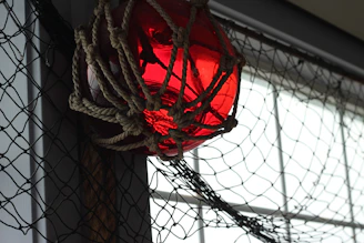 An arrangement of glowing glass floats tangled in fishing nets, casting a mystical light over textured wood and rope surfaces.
