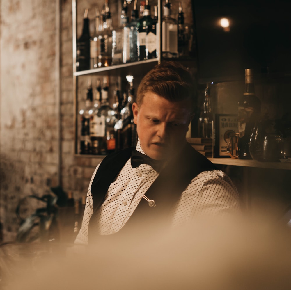 bartender standing in front of floating shelf with bottles