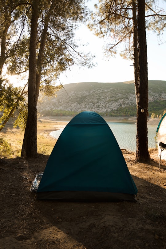 teal tent near trees and lake during day in Chera Spain