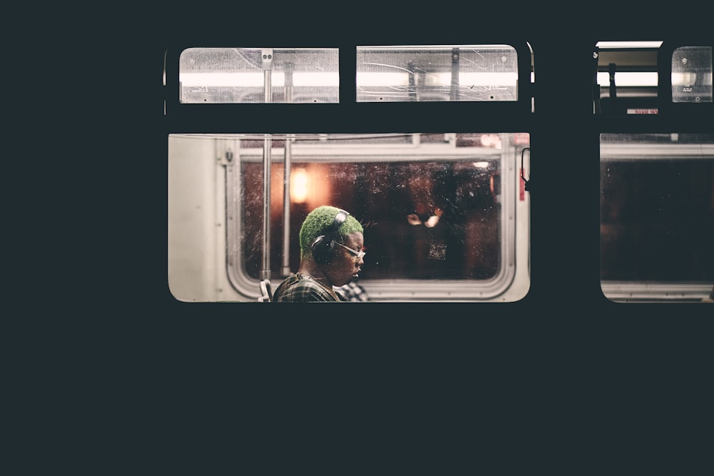 man sitting inside train wearing black headphones