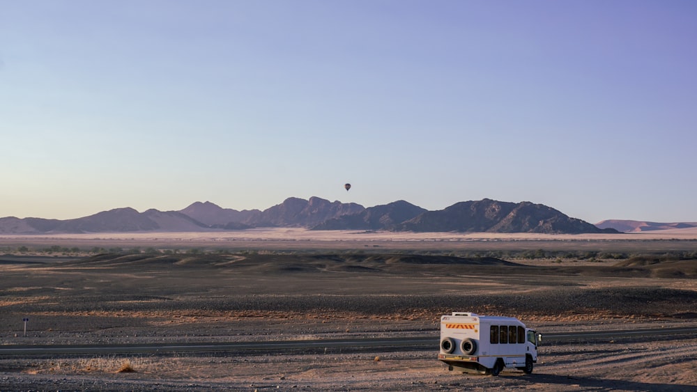 white bus on dirt road near mountain during daytime