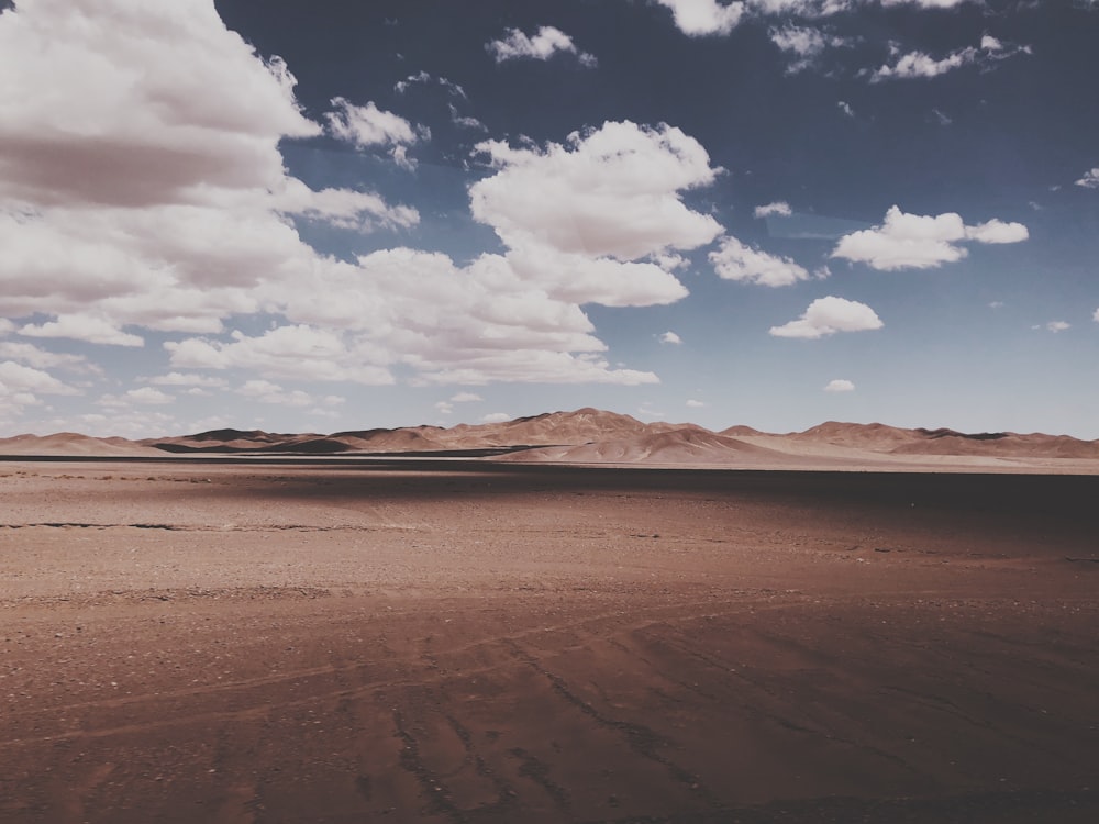 fotografia di paesaggio del deserto sotto il cielo nuvoloso durante il giorno
