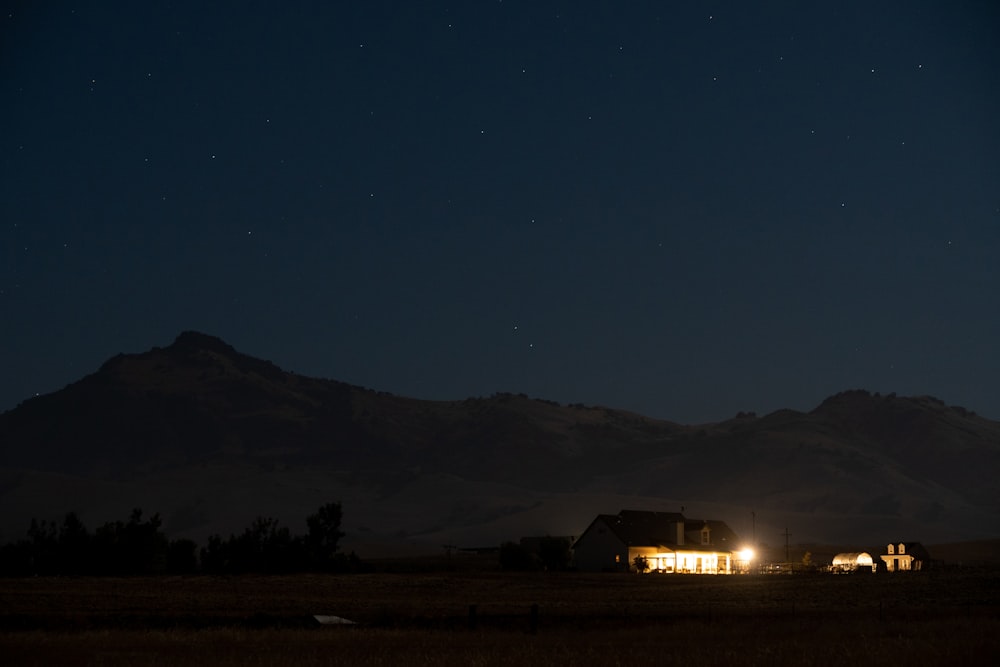 lighted light house near mountain at night