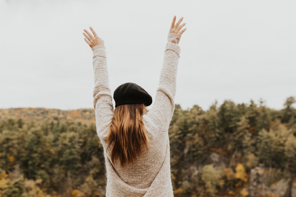 woman wearing newsboy cap raising her both arms