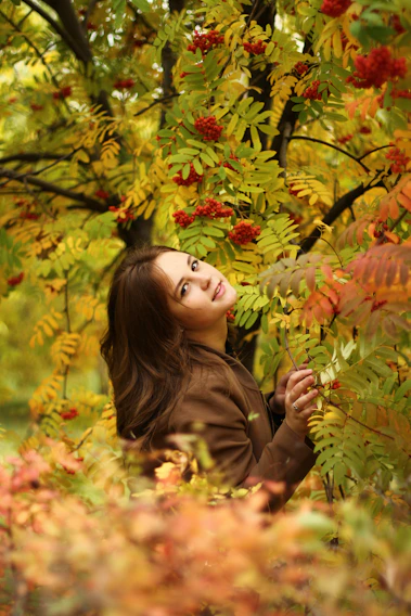 A vibrant photo of a model wearing a cozy yet stylish autumn outfit from veenora, standing against a backdrop of colorful fall leaves.