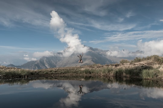 man jumps toward water under blue sky in Giumello Italy