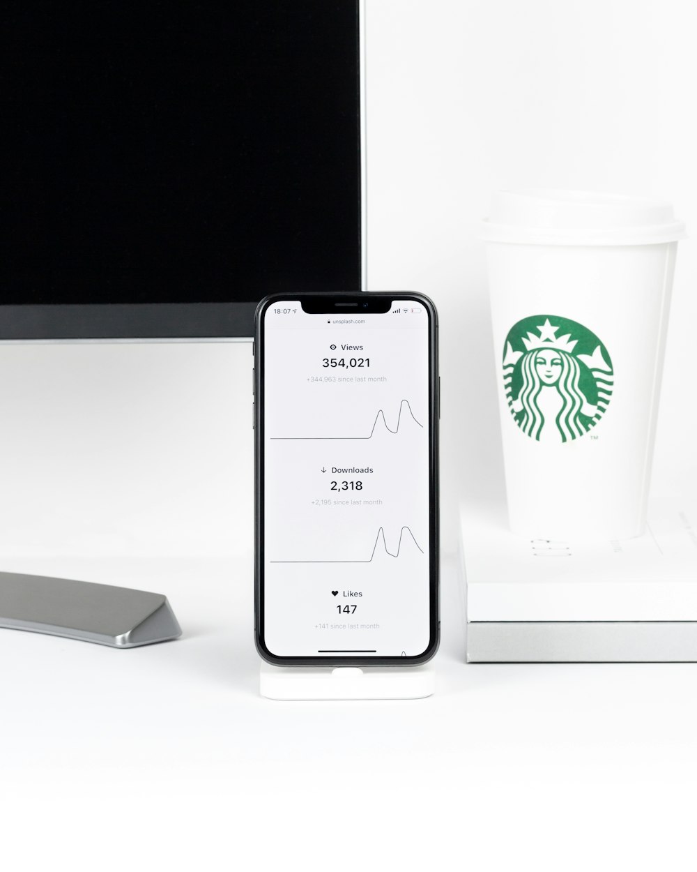 iPhone X beside Starbucks disposable cup on desk