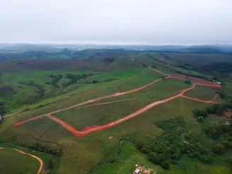 Aerial view of a vast rural farm landscape with green fields and dirt roads.
