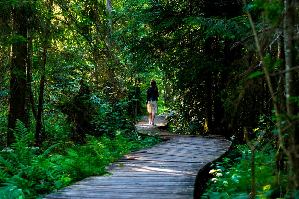 woman standing in brown pathway between trees