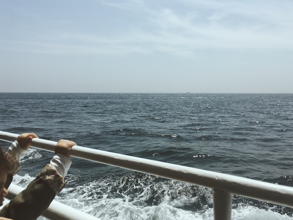 toddler holding on boat rail