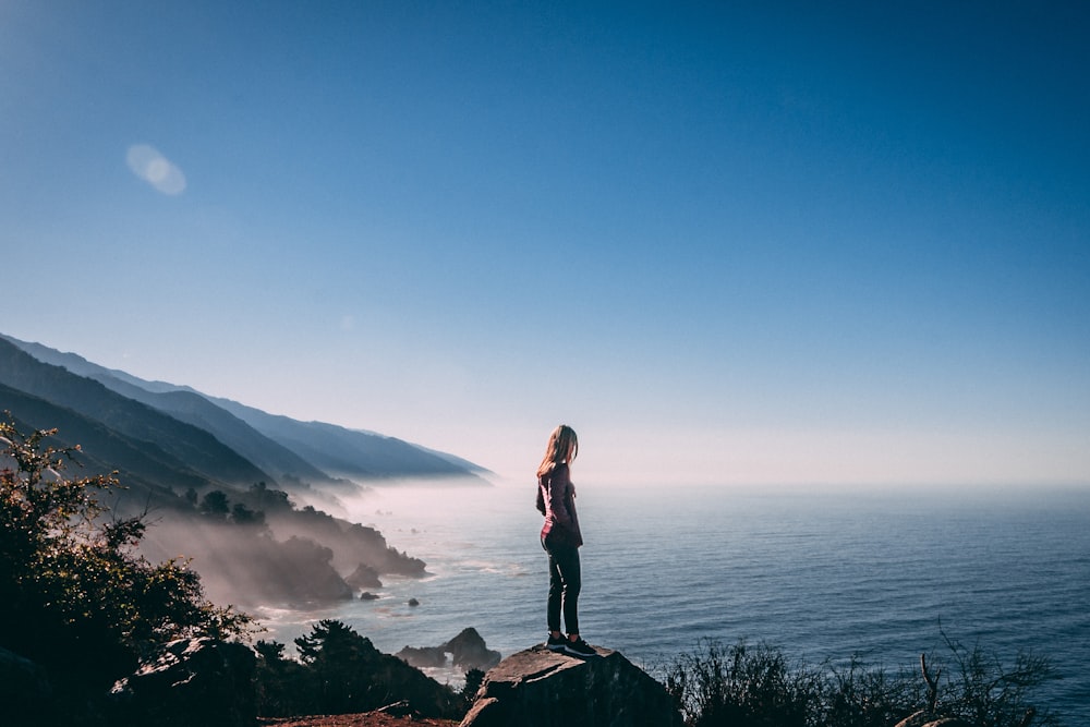 woman standing on cliff near sea