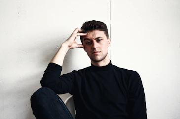 a man sitting on the floor with his hand on his head