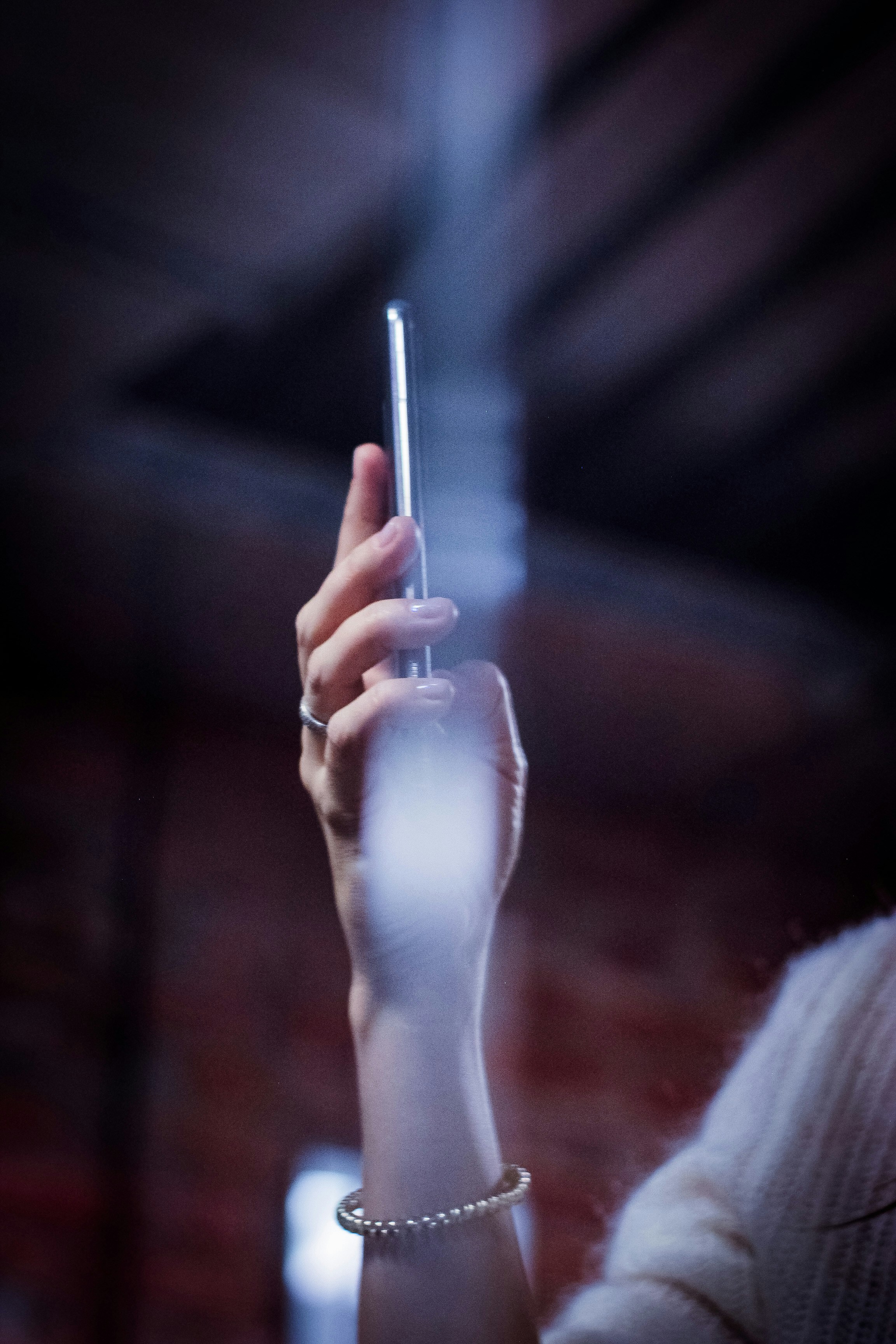 Dark smartphone with glowing app interface, deep black studio background, moody cinematic lighting