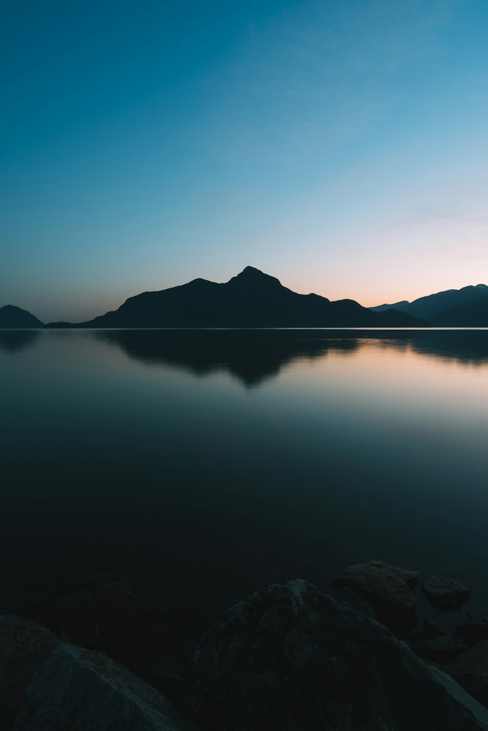 calm sea near mountain during daytime