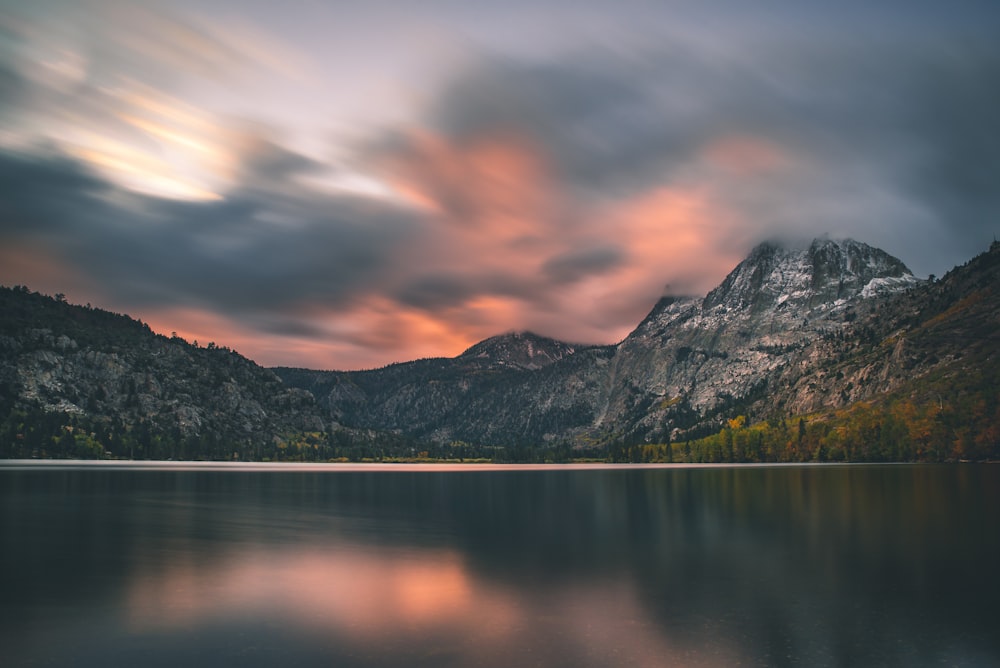 mountain range with body of water during cloudy skies