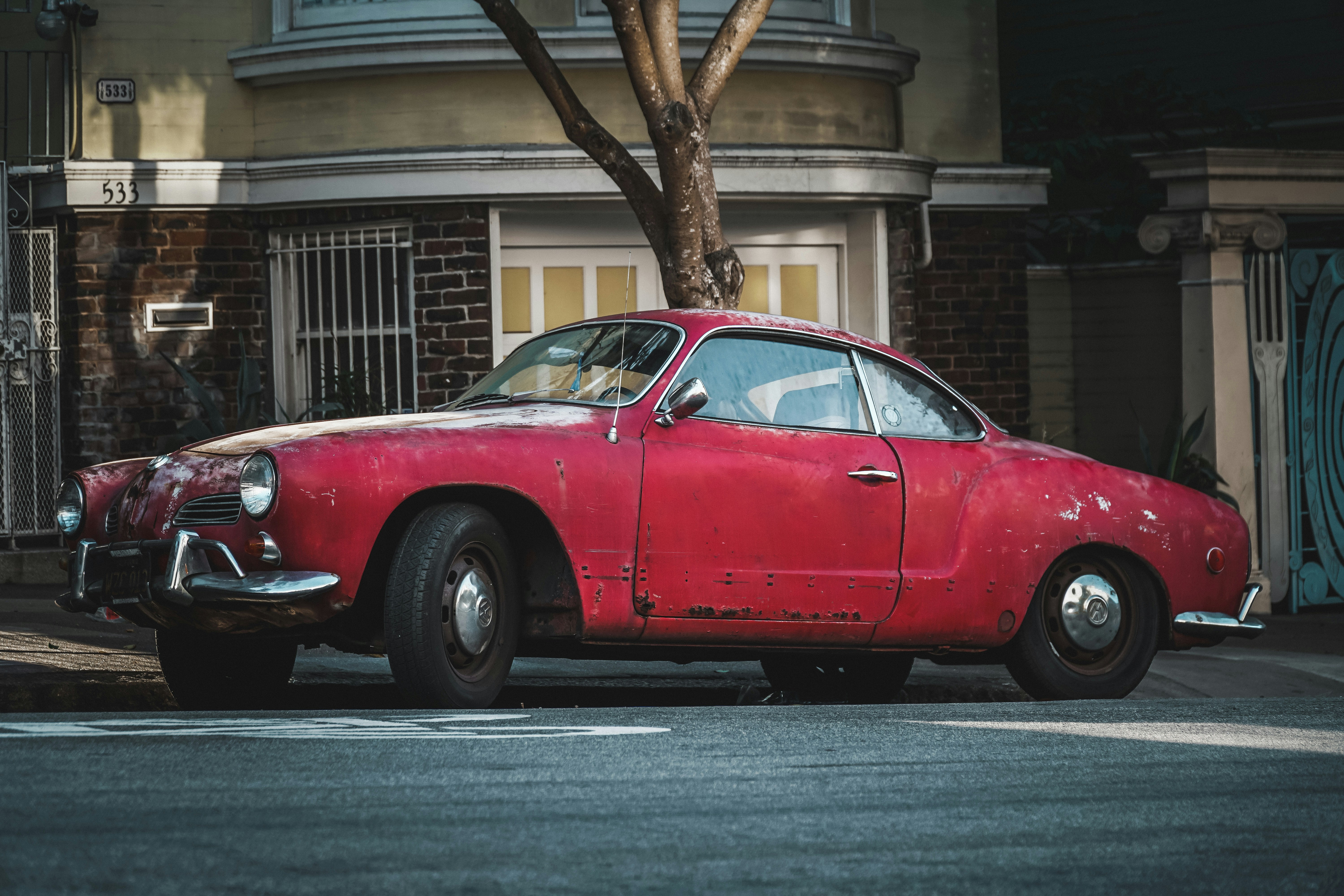 Coupé rouge classique garé à côté d’un trottoir en béton