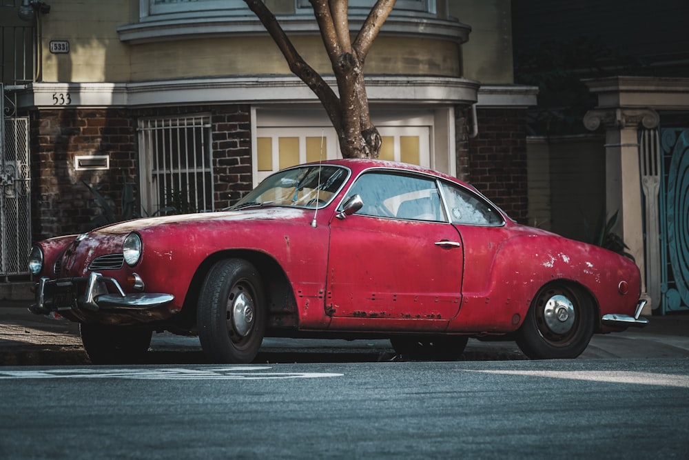 Clásico cupé rojo estacionado junto a la acera de concreto