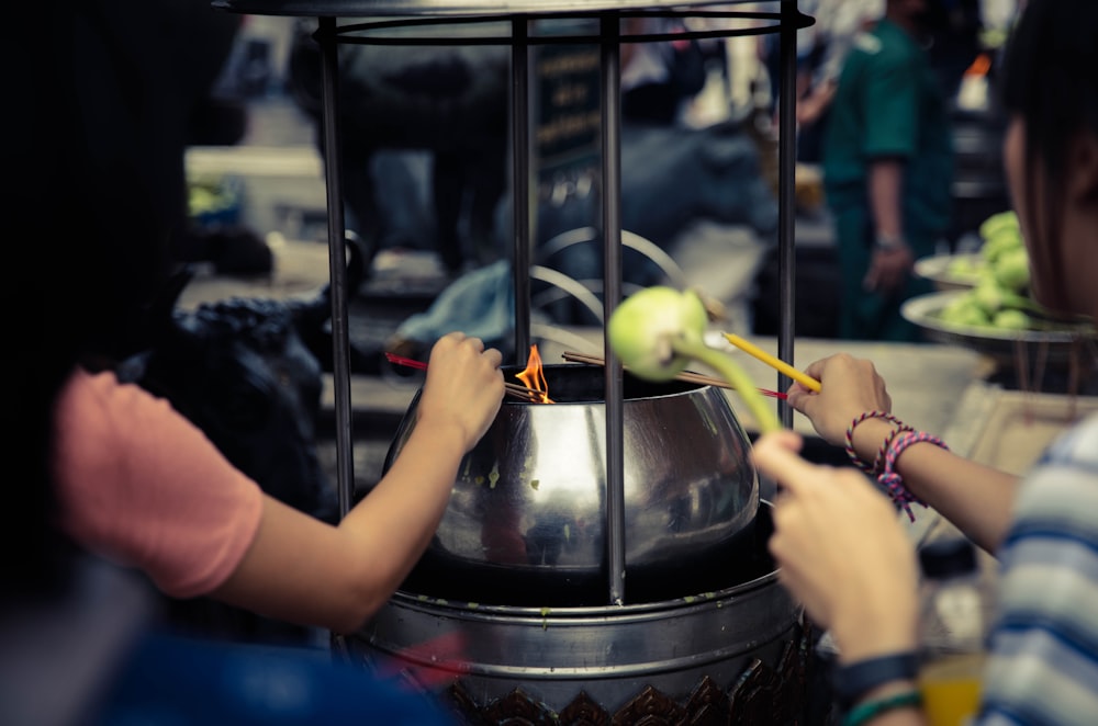 two people are cooking food in a metal pot