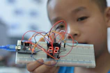 Close-up of a student programming an Arduino with vibrant LED displays.