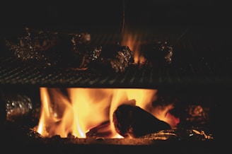 A warm, rustic grill with glowing embers and smoke rising gently, surrounded by fresh ingredients ready to be cooked.