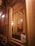 A richly decorated interior featuring ornate gold-framed mirrors, intricate moldings, and classic wall art with a natural theme. A person in a white coat walks past the mirrors, adding a modern element to the historic setting.