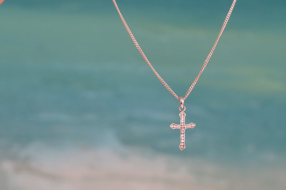 silver-colored clear gemstone encrusted cross pendant necklace in focus photography