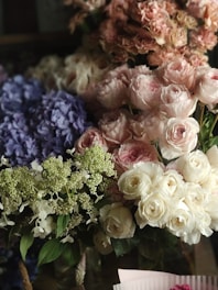 A beautiful arrangement of flowers featuring pink and white roses, purple hydrangeas, and white blossoms with green foliage.