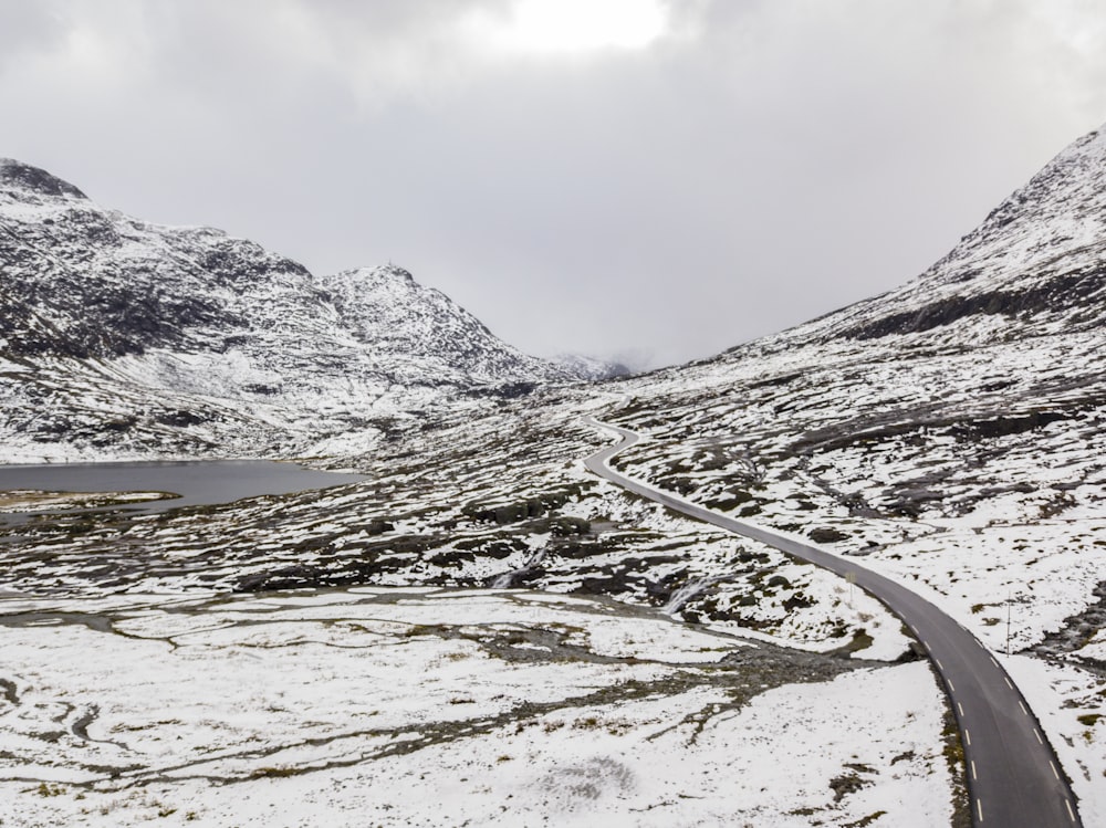 asphalt road between snow covered ground under cloudy sky