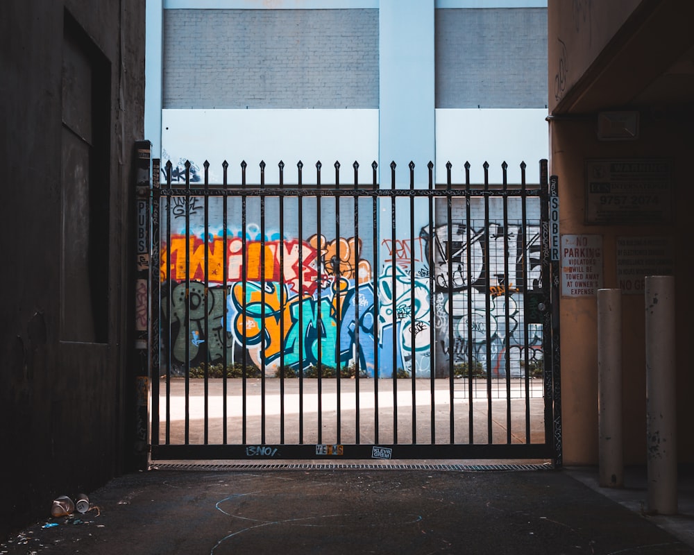 black metal gate near wall with mural