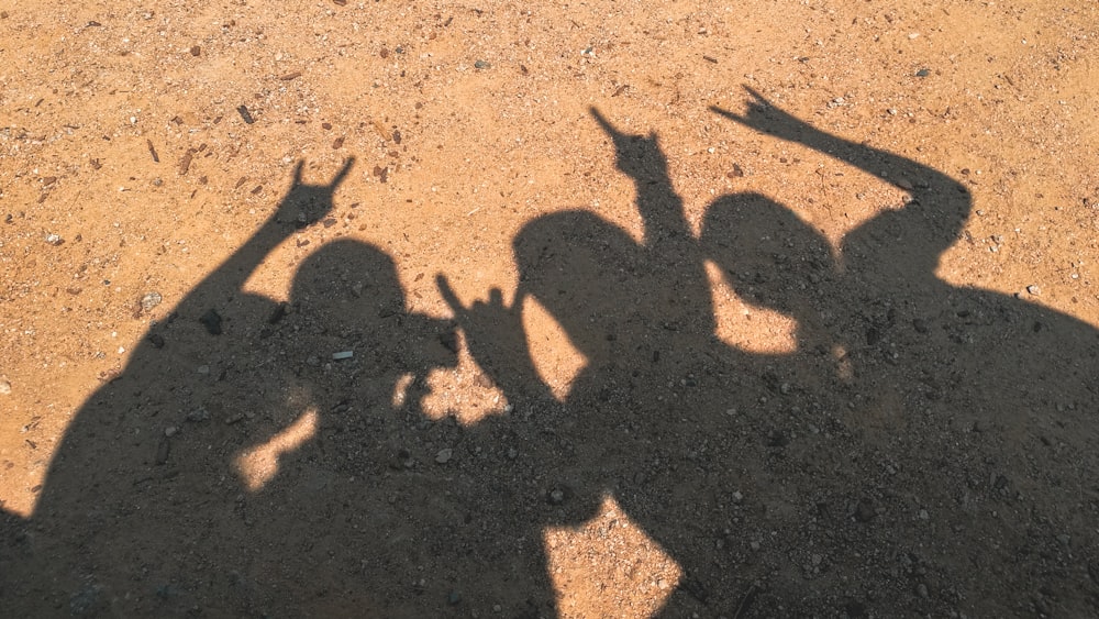 a shadow of two people on a dirt ground