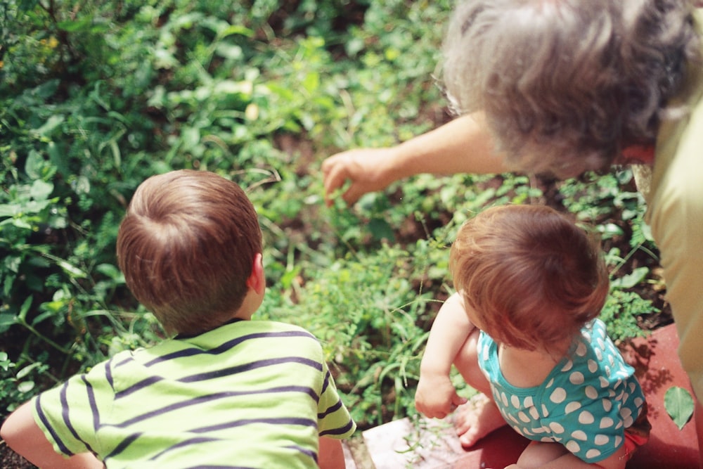 woman playing with two children in the woods