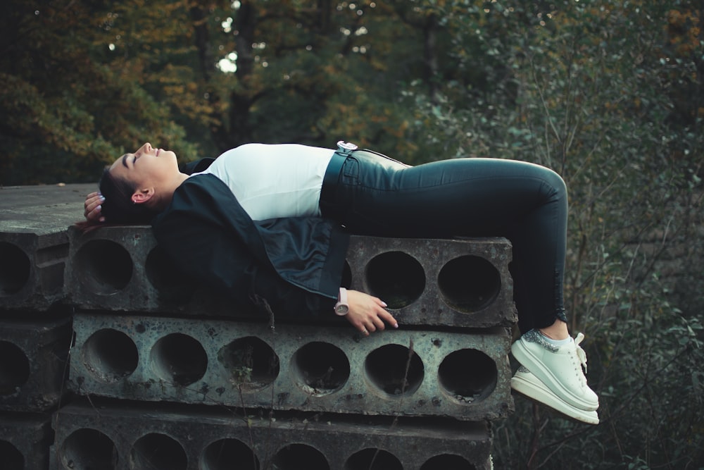 woman lying on stacked gray metal frame outdoors during daytime