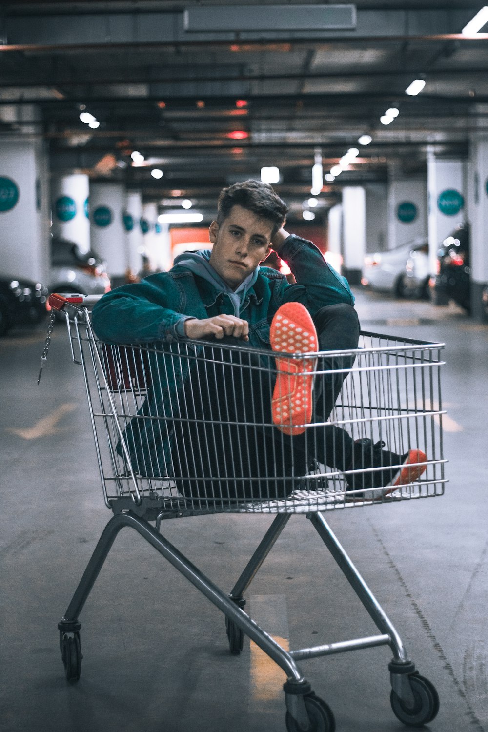 man in shopping cart inside building parking lot