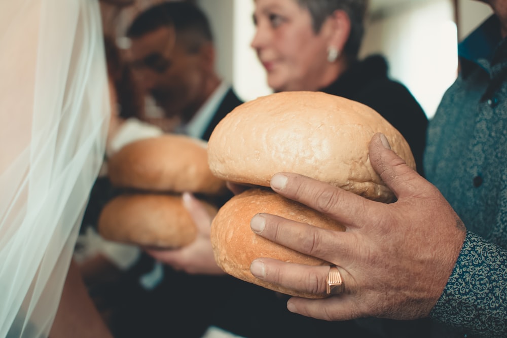 three persons holding bread