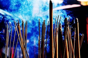 Luxurious arrangement of musk vanilla attar and jasmine oud attar with subtle incense smoke curling in the background.