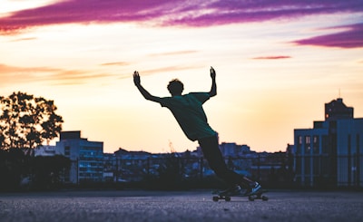 A vibrant sunset silhouette of a skateboarder jumping mid-air.