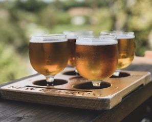 four wine glasses filled with liquid on wooden tray selective focus photography
