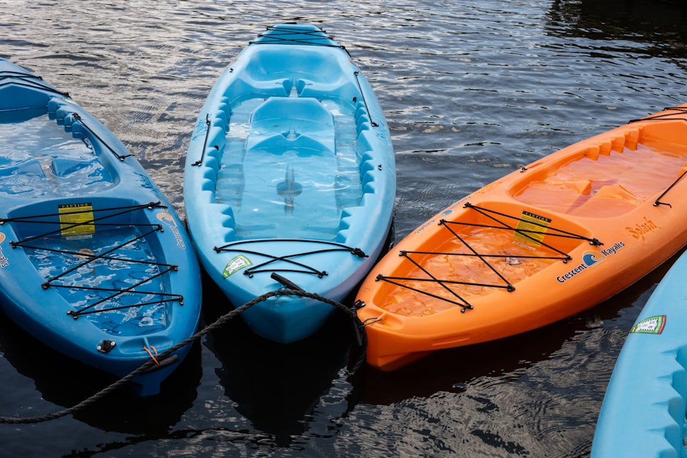 two blue and one orange kayaks on calm body of water