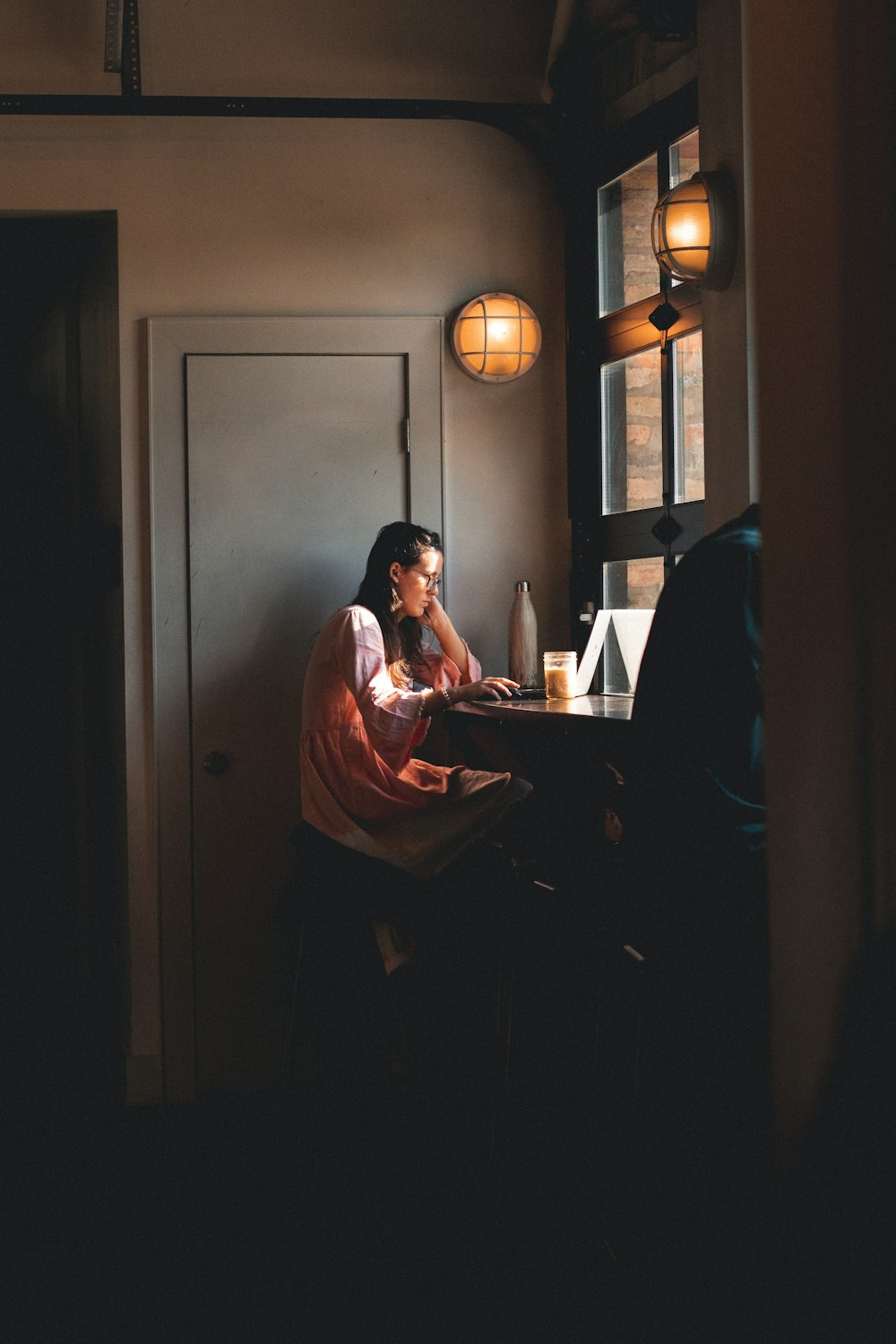 woman sitting beside closed gray door